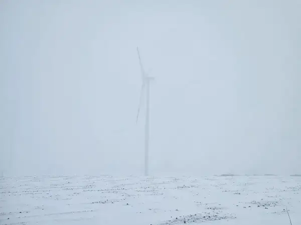 Wiatr huczy jak wiersze o smutku i żalu. Samotna turbina na zaśnieżonym polu, w mglistym, przygnębiającym krajobrazie.