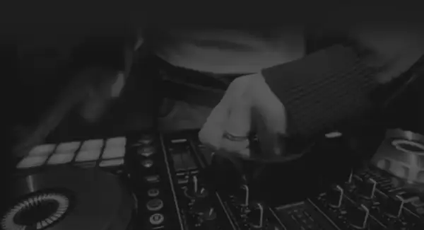 Dłoń DJ-a manipulująca pokrętłami na konsoli do miksowania muzyki.