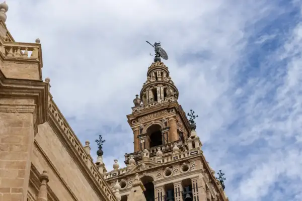 Wspaniała wieża w **Sevilla miasto** z figurą na szczycie i napisem "PROVERBIO".