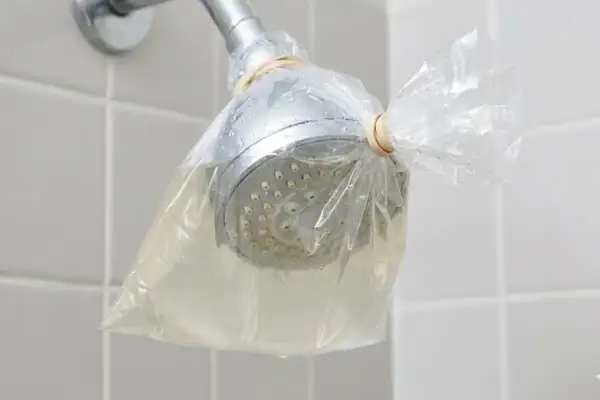Doccia con soffione avvolto in un sacchetto pieno di liquido, per rimuovere residui di autoabbronzante che si toglie con l'acqua.