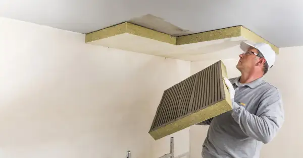Mann montiert Dämmplatten zur Deckenisolierung innen.