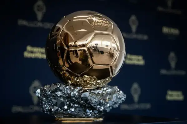 Złota Piłka, symbol triumfu na gali, lśni na tle logo France Football.