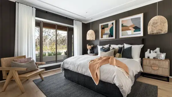 Light wood nightstands complement the dark wood bed. A cozy bedroom with a large window, rattan chair, and abstract art.
