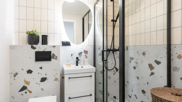 Nowoczesna metamorfoza łazienki: białe płytki, beton architektoniczny i czarne detale tworzą stylową przestrzeń.