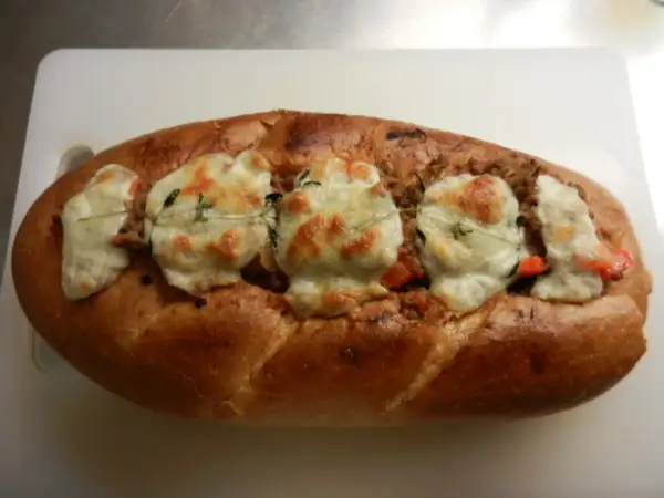 En gyllene, fylld fransk baguette med smält ost och örter.
