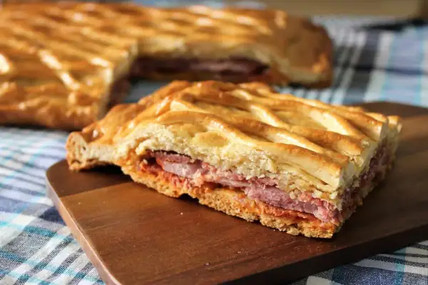 Un delicioso hornazo de Pascua, con su masa dorada y relleno de carnes, listo para compartir.