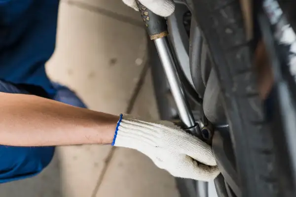 Mechanik w białej rękawicy dokręca śruby koła kluczem dynamometrycznym, dbając o to, z jaką siłą dokręcać koła.