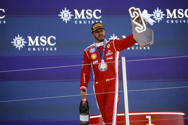 Lewis Hamilton celebra su victoria en el podio, con trofeo y champán. Su edad no se refleja en su energía.