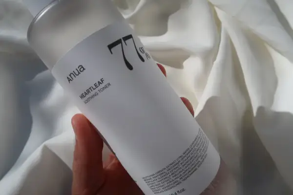 Anua Heartleaf Soothing Toner 77% w dłoni na tle białej tkaniny. Idealny do codziennej pielęgnacji.