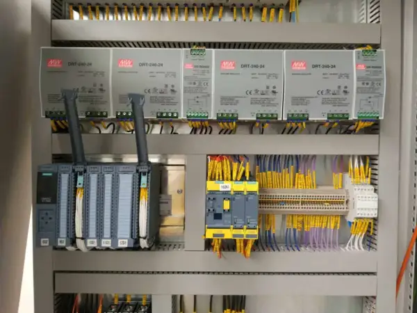 Panel sterowania z zasilaczami MW DRT-240-24, sterownikiem Siemens S7-1500 i żółtymi przewodami. Akpia.