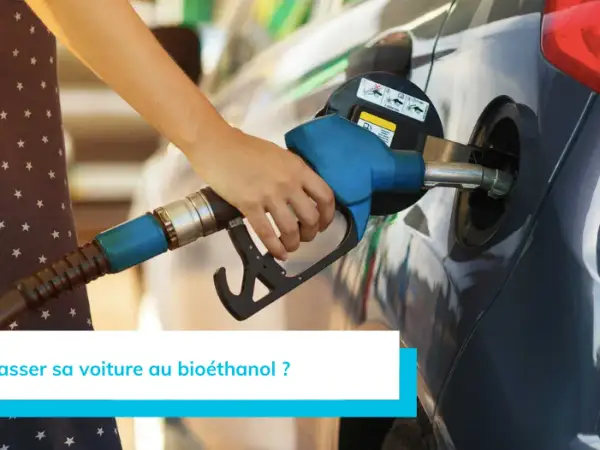 Main d'une personne tenant un pistolet de pompe à essence pour faire le plein d'une voiture. Recherche d'une liste voiture compatible e85 sans kit pour rouler plus vert.
