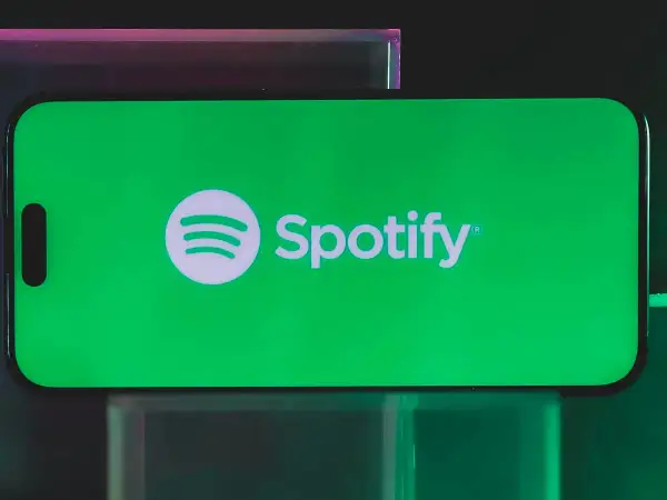 A smartphone displays the Spotify logo on a vibrant green screen, hinting at a free distributor for Spotify.