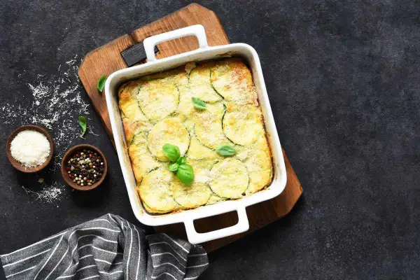 Sformato dorato con zucchine e patate, guarnito con basilico fresco. Un'idea gustosa per le tue ricette con zucchine e patate.