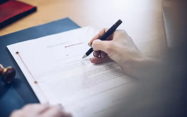 Dłoń pisze piórem na dokumencie testamentu. To ważny testament allograficzny, który określa przyszłość.