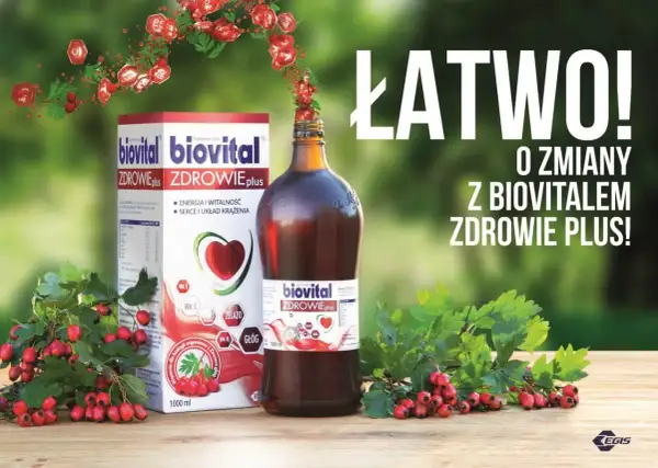 Biovital Zdrowie Plus – suplement diety z głogiem i witaminami. Pudełko i butelka na drewnianym stole, otoczone gałązkami z czerwonymi owocami.