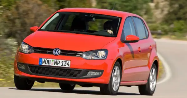 Czerwony vw polo 2010 na zakręcie drogi.