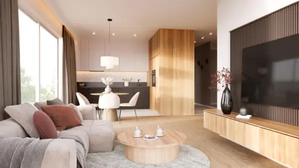 Przytulny salon z elementami stylu japandi: jasna sofa, drewniany stolik kawowy, kuchnia z wyspą i jadalnia.