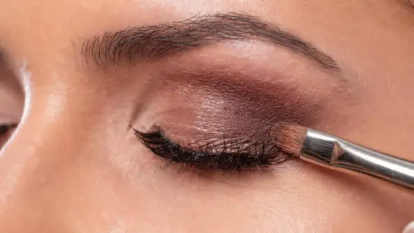 Aplicando sombra marrón con brocha. Aprende como maquillar los ojos a partir de los 50 años para un look elegante y natural.