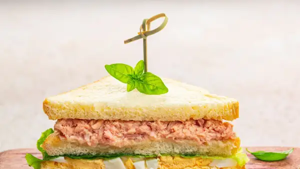 Tramezzini veloci con tonno, uova e lattuga, guarniti con basilico fresco. Perfetti per un pasto rapido e gustoso.