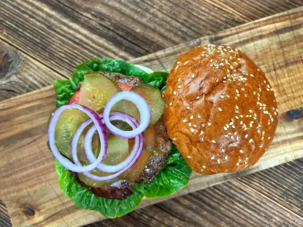 Pyszne burgery wołowe z piekarnika, z chrupiącą bułką, sałatą, ogórkiem i czerwoną cebulą.