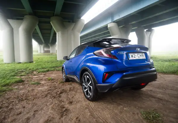 Niebieski Toyota C-HR 2018 zaparkowany pod mostem.