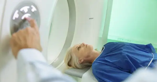 Pacjentka leży na stole do badania, a technik przygotowuje badanie tk.