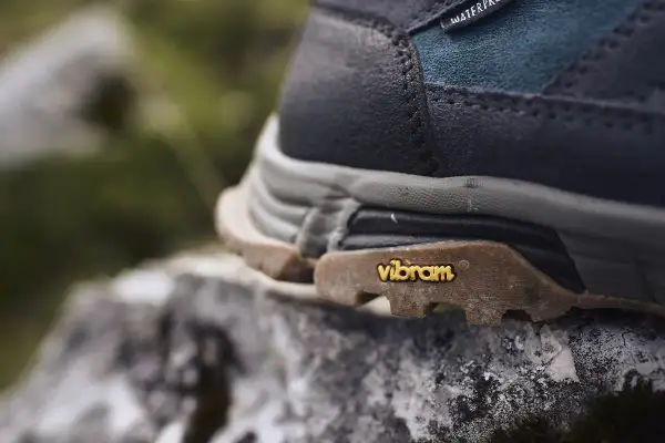 Nahaufnahme eines Wanderschuhs mit Vibram-Sohle auf einem Stein. Mögliche vibram sohle nachteile wie Abnutzung sind hier nicht sichtbar.