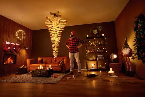 Mann steht vor umgedrehtem Holz-Weihnachtsbaum mit Lichtern. Tolle alternativen zum Weihnachtsbaum für ein modernes Zuhause.