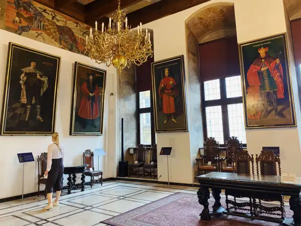 Wielka sala z portretami królów i bogatym żyrandolem. Sprawdź muzeum narodowe w gdańsku godziny otwarcia, by zobaczyć to na żywo.