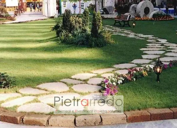 Un sentiero sinuoso di pietre irregolari attraversa un prato verde, creando un passaggio suggestivo nel giardino.