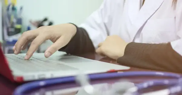 Lekarz wpisuje dane pacjenta na laptopie, co oznacza skierowanie na cito. Stetoskop leży obok.