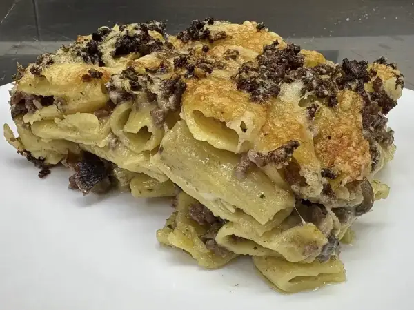 Un invitante piatto di pasta al forno, la ricetta della nonna, con pasta rigata, ragù e formaggio filante.