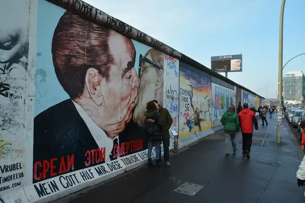East Side Gallery Berlin: para zakochanych całuje się na tle słynnego malowidła "Braterki" Breżniewa i Honeckera.