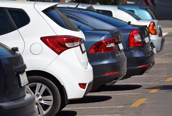 Rzędy samochodów na parkingu, w tym biały i ciemny, mogą być pomocne, gdy zastanawiasz się, jak sprawdzić auto ze Szwecji.