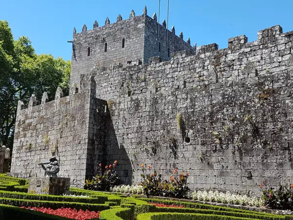 El imponente castillo de Sotomayor se alza sobre un jardín cuidado, con sus muros de piedra y almenas bajo un cielo azul.