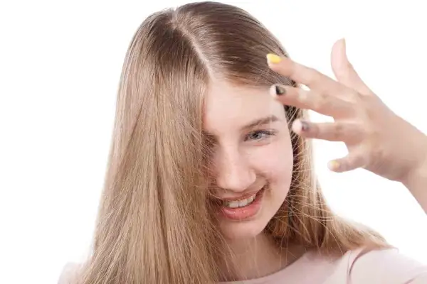Chica sonriente con cabello rubio que se electrifica. Descubre cómo quitar la electricidad del pelo para un look suave.