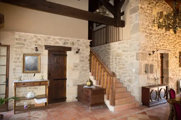 Interior de una casa antigua con paredes de piedra, vigas de madera y una escalera. Un proyecto de reformar casa antigua que conserva su encanto rústico.