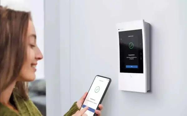 Une femme utilise son smartphone pour configurer un interphone Bticino Classe 300. L'écran affiche "Completato".