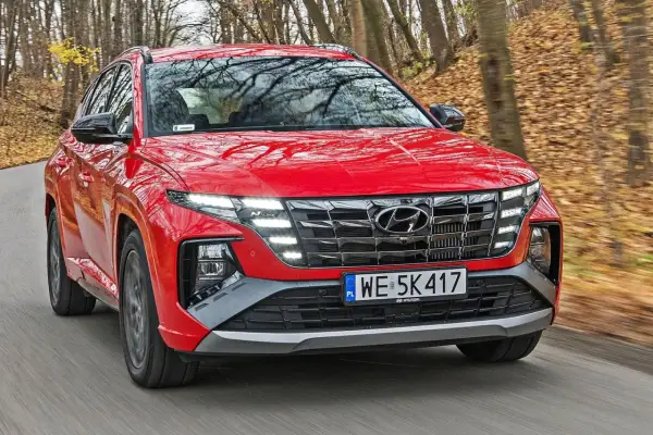 Czerwony Hyundai Tucson N Line w ruchu, z widoczną długością maski i grillem.