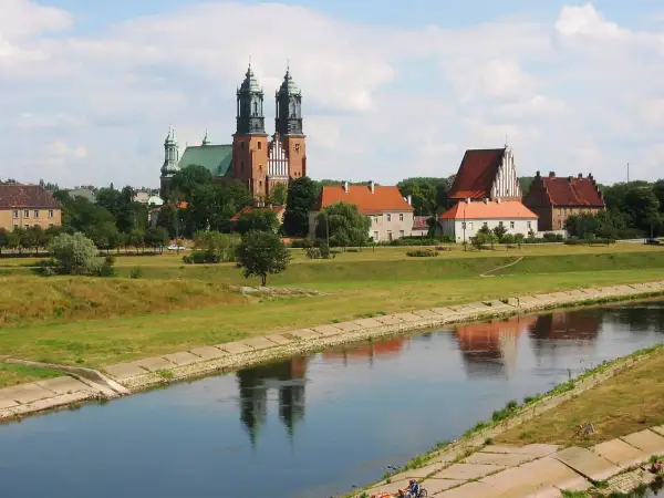 Widok na Ostrów Tumski w Poznaniu z katedrą i innymi zabytkowymi budynkami nad rzeką Wartą.