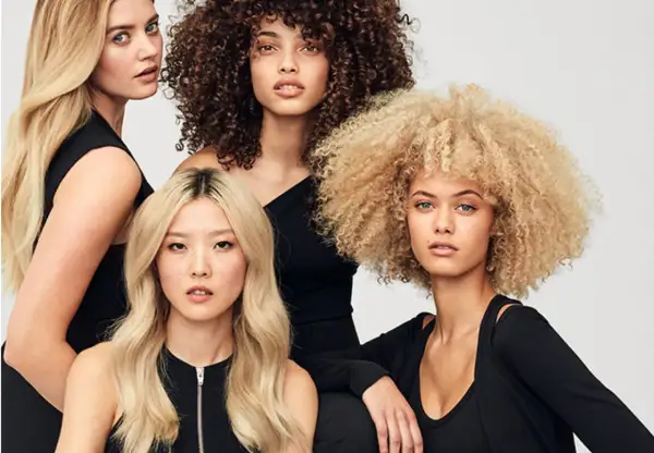Fyra kvinnor med olika hårtyper: rakt, lockigt och afro. Alla har slitet hår som ser friskt ut.