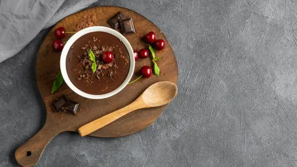 Pyszny budyń czekoladowy z wiśniami i miętą. Zastanawiasz się, ile kcal ma budyń czekoladowy? Ten deser wygląda na bogaty w smak!