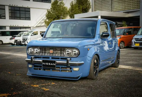 Niebieski Nissan Cube z chromowanymi zderzakami i grillem, obniżonym zawieszeniem i czarnymi felgami.
