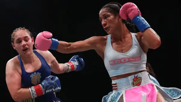 A boxer lands a powerful jab, her opponent reeling from the impact. The intensity of the fight is palpable, showcasing the raw emotion and skill involved in boxing terms.