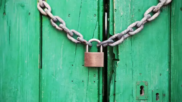 Puerta verde cerrada con cadena y candado. Un símbolo de que se puede quitar el usufructo de una vivienda.