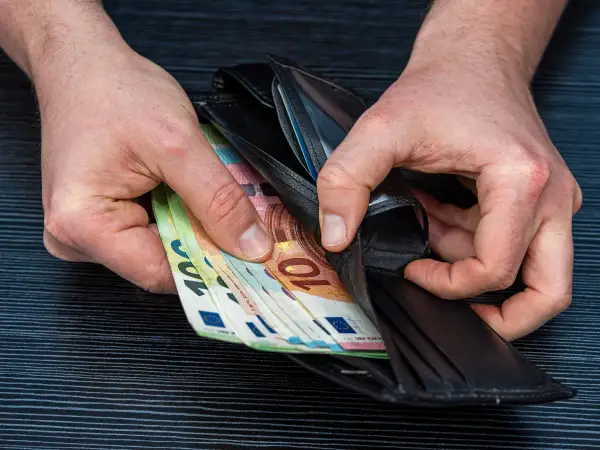 Ręce wkładają do portfela banknoty euro. Zarobione pieniądze po ciężkiej pracy lakiernika.