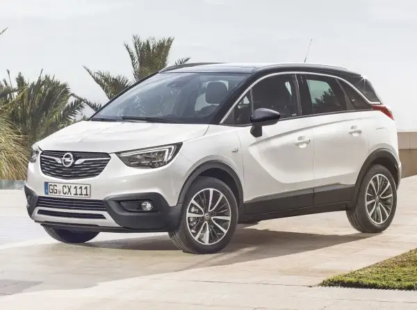 Biały Opel Crossland z czarnym dachem, zaparkowany na tarasie z palmami w tle. Wiele pozytywnych opinii o tym modelu.