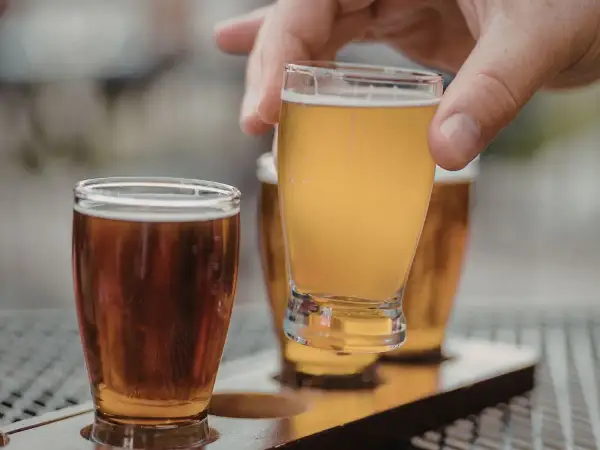 Assaggio di una fresca italian pale ale dorata, con un'altra birra ambrata in primo piano.