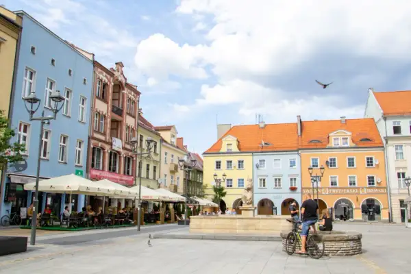 Kolorowy rynek w Gliwicach, idealne miejsce na weekendowe atrakcje. Ludzie siedzą w ogródkach kawiarnianych, a w tle widać zabytkowe kamienice.