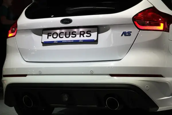 Biały Ford Focus RS z podwójnym wydechem i niebieskim znaczkiem RS.